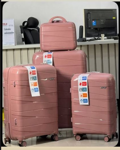 Set of pink suitcases with tags on a desk background
