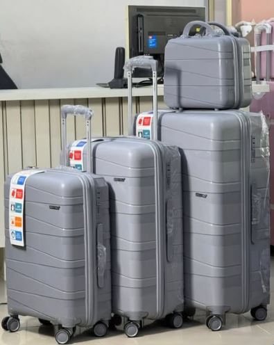 Set of gray suitcases of different sizes with a suitcase on top in an indoor setting.