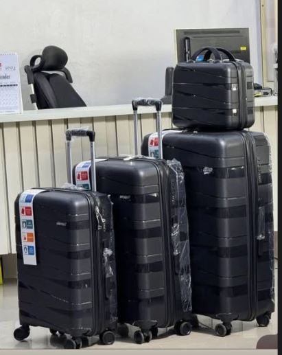 Set of black suitcases of different sizes stacked and arranged in a store setting.
