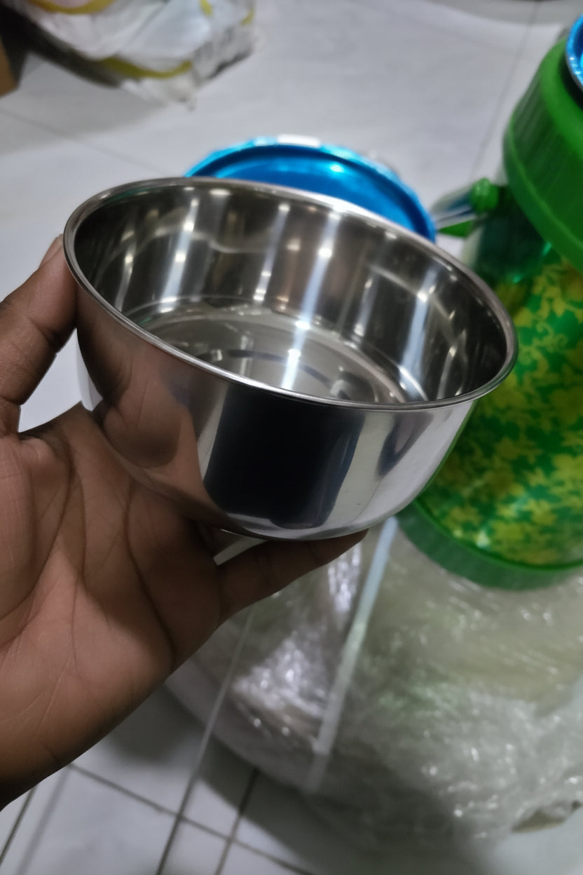 Metallic cup held by a hand with a green container in the background