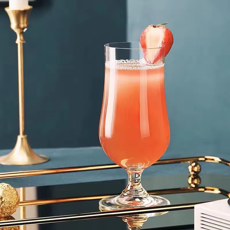 Cocktail in a tall glass with a red fruit on a bar tray against a dark background