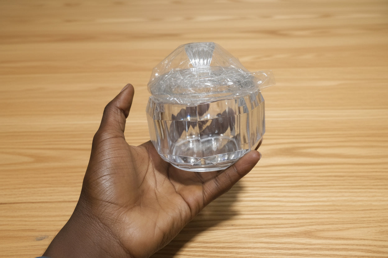 Hand holding a clear plastic container with a lid against a background of stacked white containers.