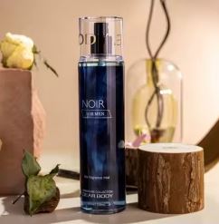 Blue skincare product bottle labeled 'NOIR' on a wooden surface with decorative elements.