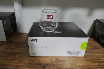 Clear glass mug leaning against a Cuisinart glassware box on a white surface.