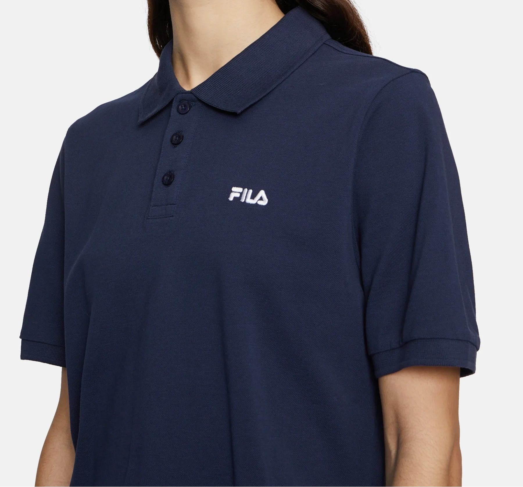 Woman wearing a navy blue polo shirt with Fila logo on a white background