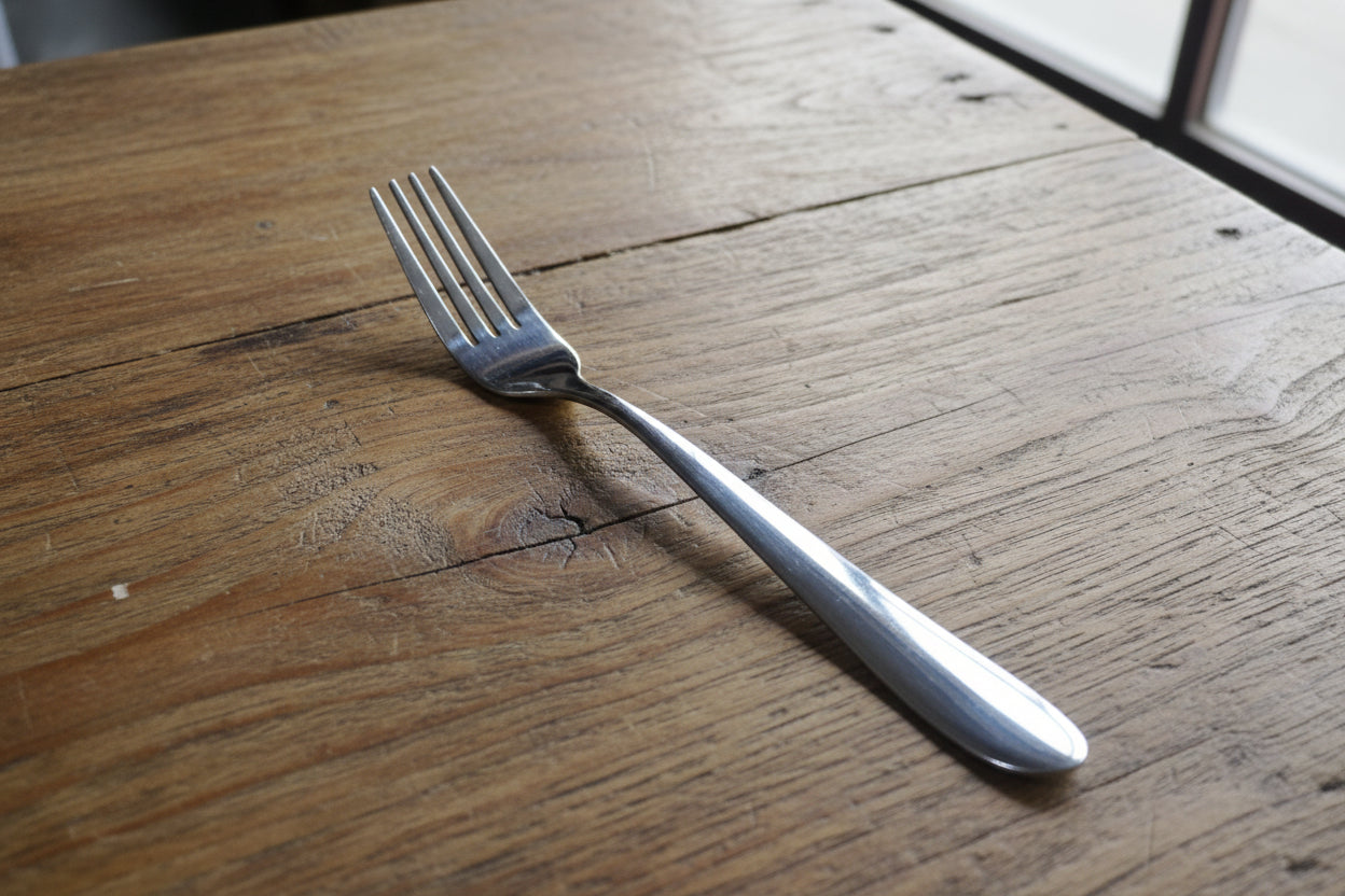 Hand holding a fork with a blurred background of bottles and boxes