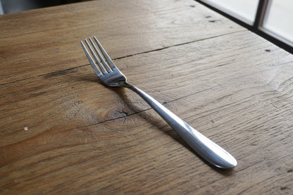 Hand holding a fork with a blurred background of bottles and boxes