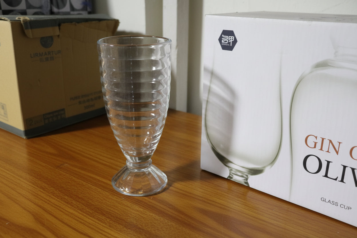 Clear glass on a shelf with boxes and a patterned rug in the background