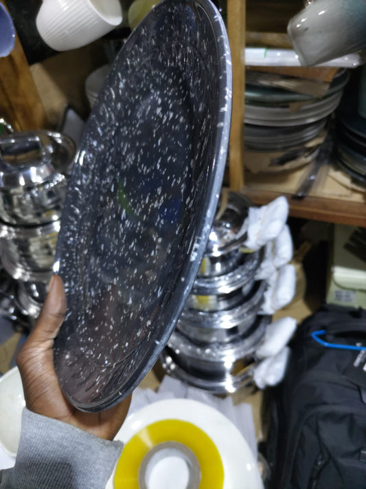 Hand holding a speckled glass plate with kitchenware in the background