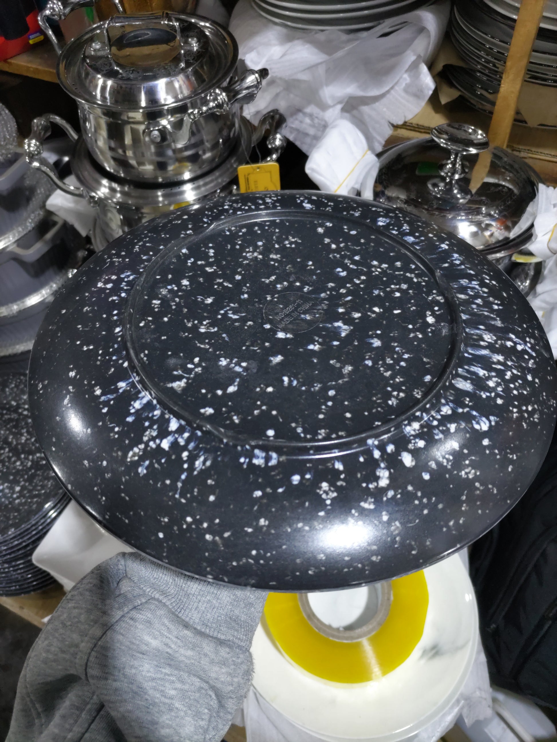 Black speckled plate on a cluttered background with various kitchen items.