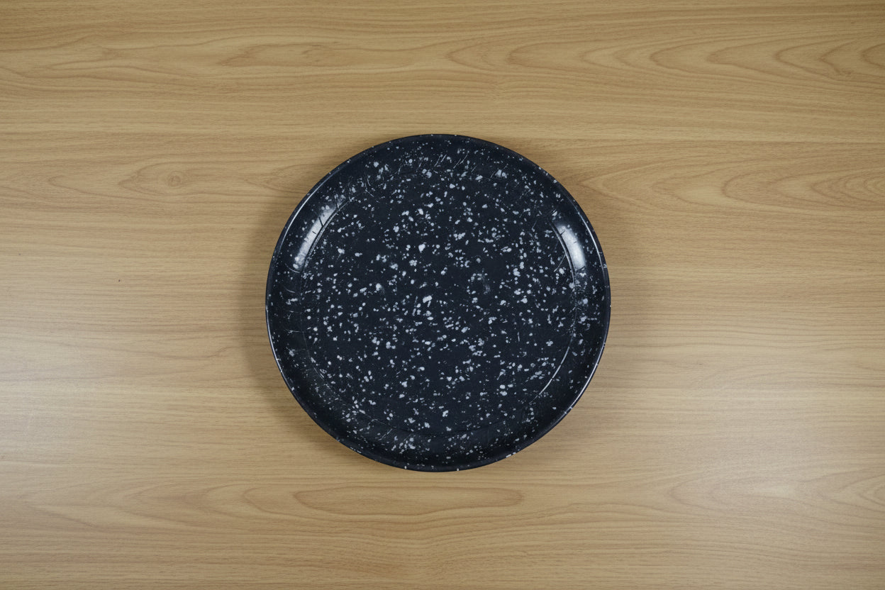 Black speckled frying pan held by a person in a cluttered store setting