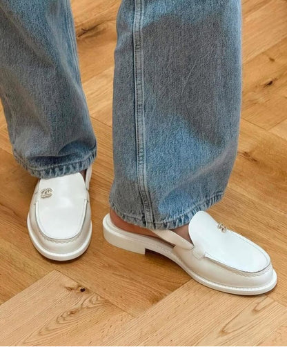 White loafers worn with blue jeans on a wooden floor