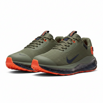 Two green running shoes with orange accents on a wooden floor.