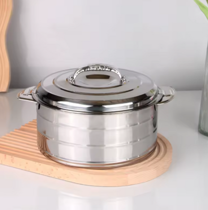 Stainless steel pot with lid on a wooden trivet