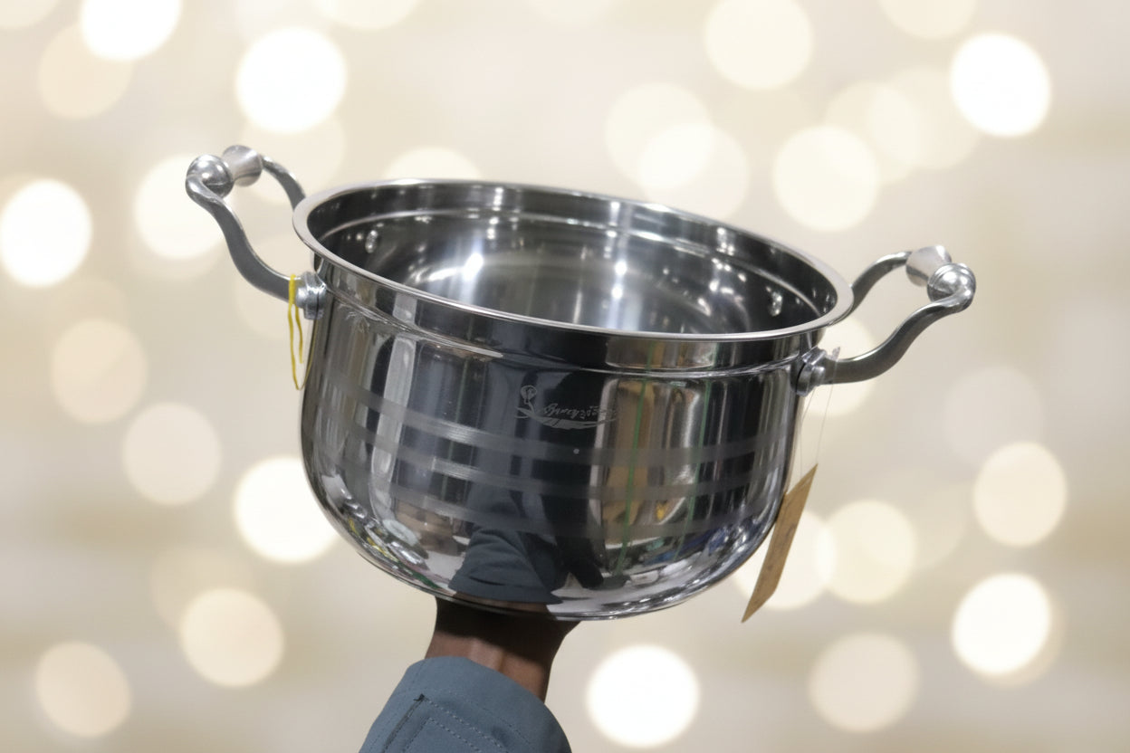 Stainless steel pot on a cluttered surface with various items in the background