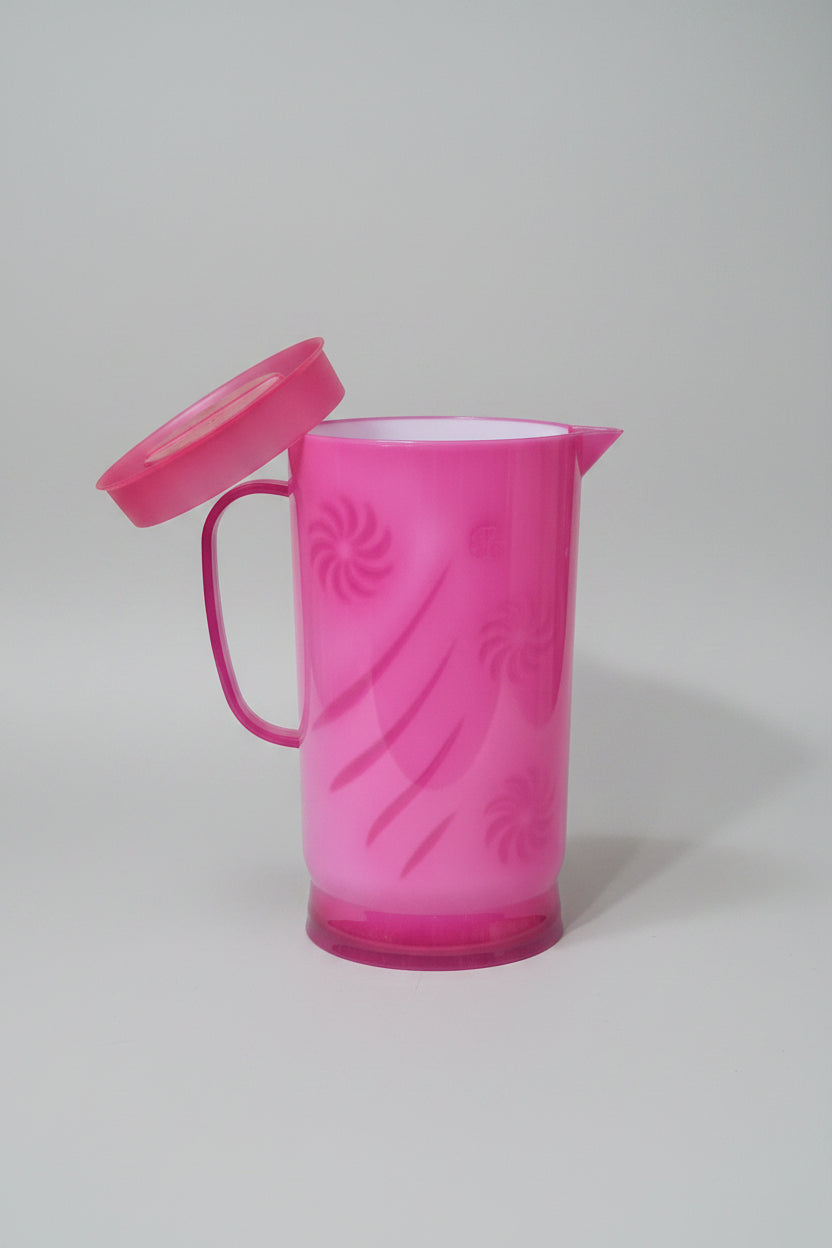 Pink plastic cup with lid held by a hand against a cluttered background