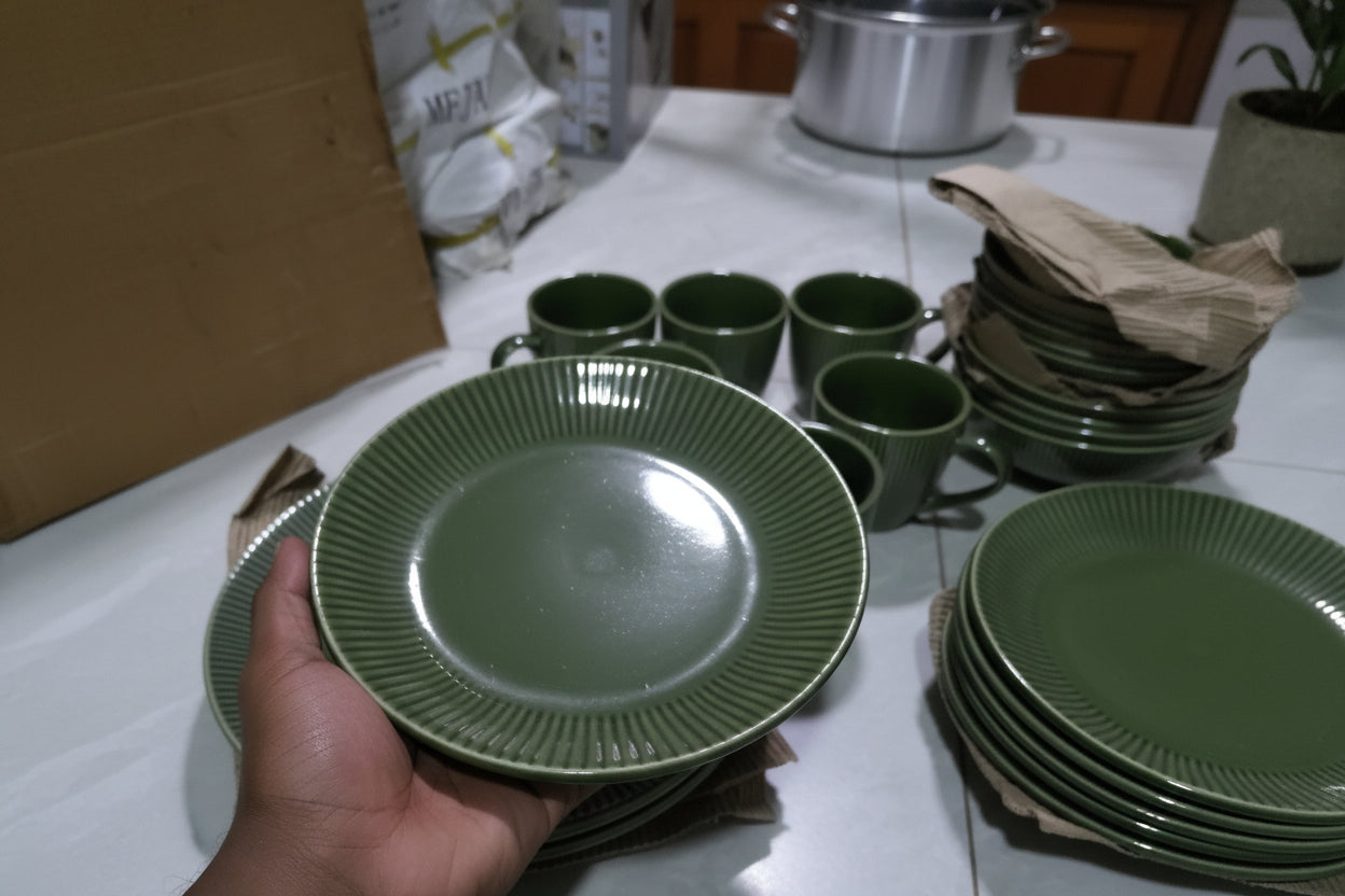 Green ceramic plates and cups on a tiled floor