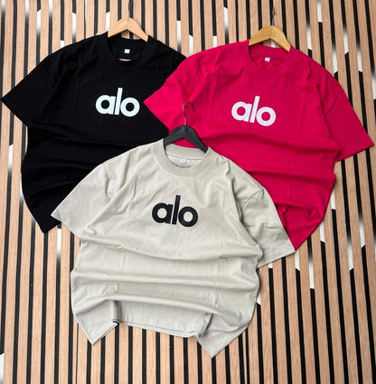Three t-shirts in black, red, and gray with 'alo' logo on a striped background