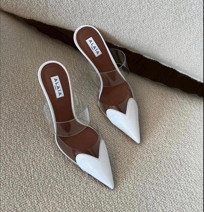 Pair of brown and white shoes with 'Alaia' branding on a beige surface.