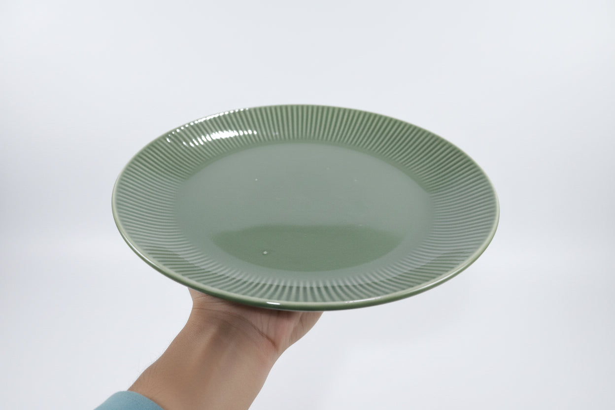 Green ceramic bowl with other green ceramic items in the background