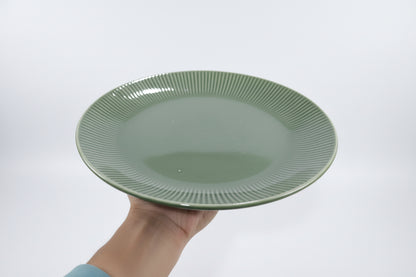 Green ceramic bowl with other green ceramic items in the background