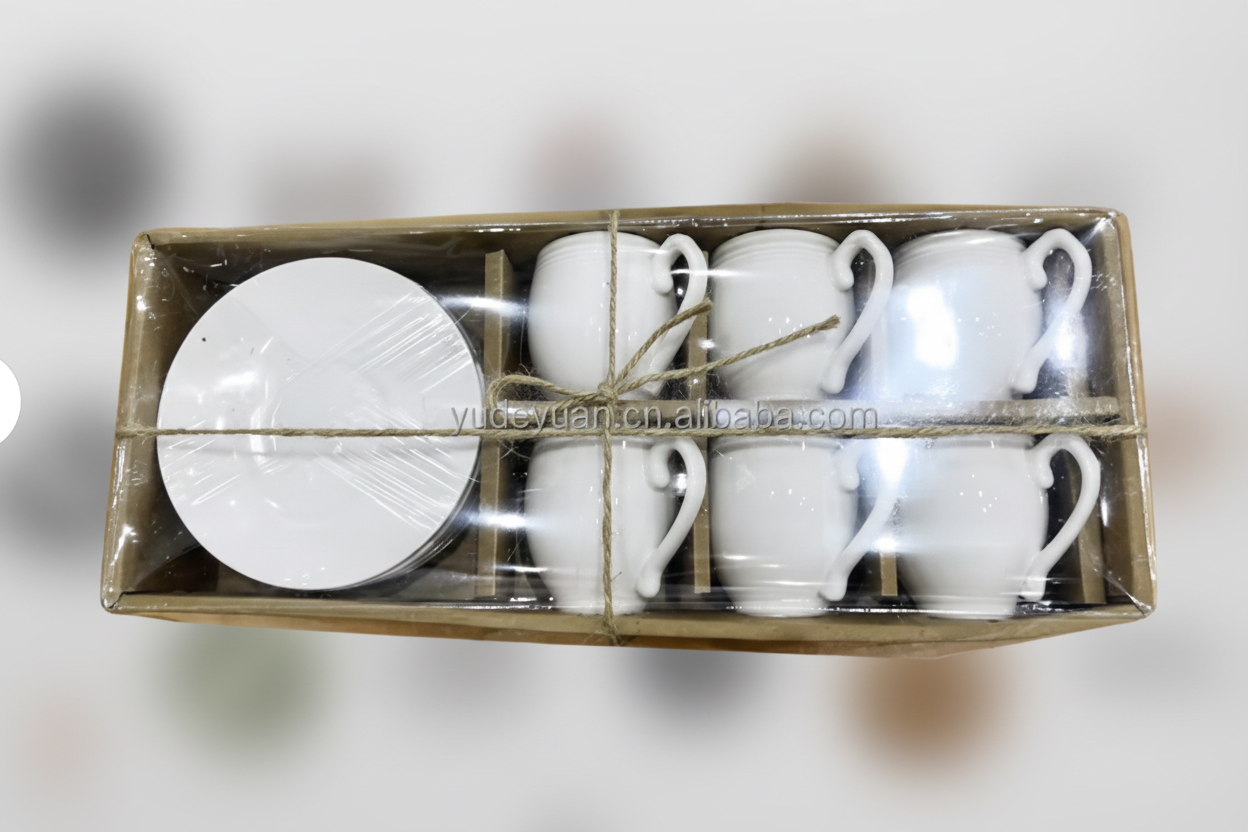 Set of white ceramic mugs and saucers in a cardboard box on a white background