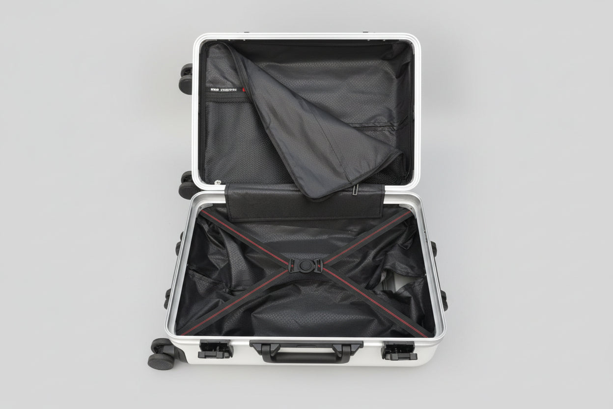 Open suitcase with black interior and red zippers on a textured surface.