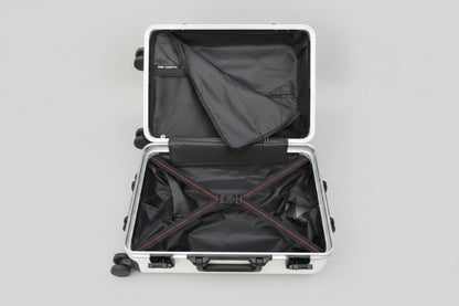 Open suitcase with black interior and red zippers on a textured surface.