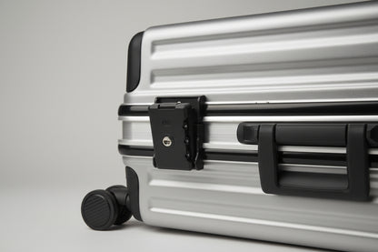 Silver suitcase with a handle and wheels on a textured surface