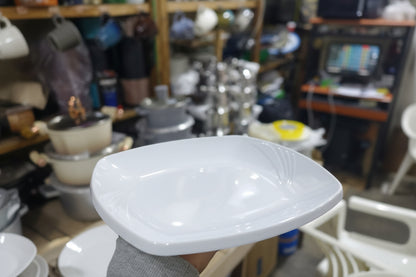 Close-up of a large white light fixture in a cluttered workshop.