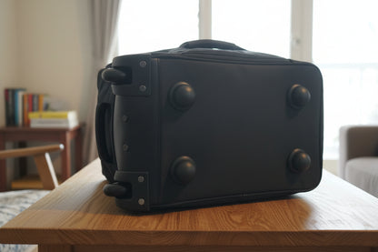 Black suitcase with wheels being held by a person in an indoor setting