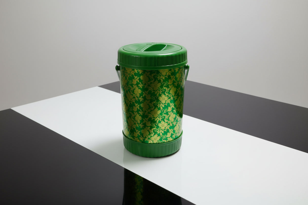 Green and yellow container on a cluttered surface with plastic wrap
