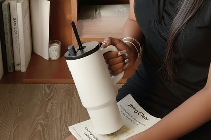 Person holding a white tumbler with a widened handle, sitting on a wooden floor.