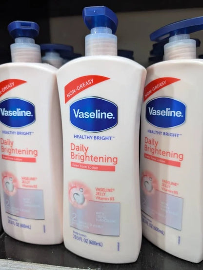 Three bottles of Vaseline Daily Brightening lotion on a black surface.