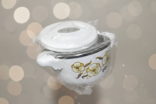 White ceramic pot with floral design on lid, wrapped in clear plastic, amidst other kitchen items.